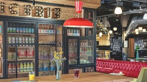 Un interior de restaurante con barra de madera, asientos rojos y un cartel sobre la barra.