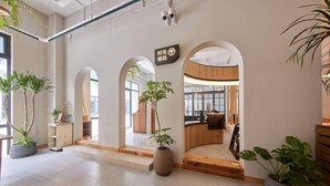 A spacious lobby with arched doorways, potted plants, and a sign indicating a restroom. - Yitel Hotel Shanghai Hongqiao Airport Lianming Road Branch (Shanghai)