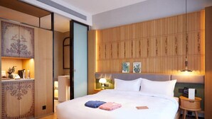 A hotel room with a large bed, a wooden headboard, a nightstand with a lamp, and a wall with vertical wooden slats. - Yitel Hotel Shanghai Hongqiao Airport Lianming Road Branch (Shanghai)