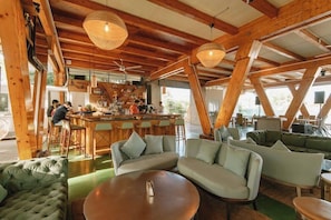 A spacious, open-plan bar area with wooden beams and hanging light fixtures. There are several seating areas with sofas and a round table. - Asmara Urban Resort and Lifestyle Village Powered by Aston (Cebu City)