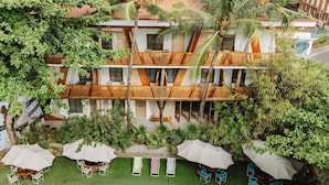 A multi-story hotel with outdoor seating areas, palm trees, and a well-maintained lawn. - Asmara Urban Resort and Lifestyle Village Powered by Aston (Cebu City)