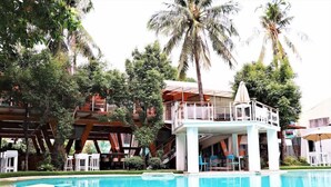 A pool area with a lounge chair, a small table, and a covered seating area with umbrellas. - Asmara Urban Resort and Lifestyle Village Powered by Aston (Cebu City)