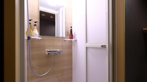 A bathroom with a shower, a toilet, and a mirror. There are toiletries on a shelf. - Onyado Nono Matsumoto Natural Hot Spring (Matsumoto)