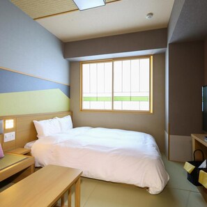 Ein Hotelzimmer mit Bett, Schreibtisch, Stuhl, Fernseher und Fenster.