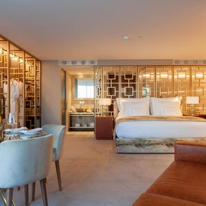 Una habitación de hotel con cama, zona de estar, armario y espejo.