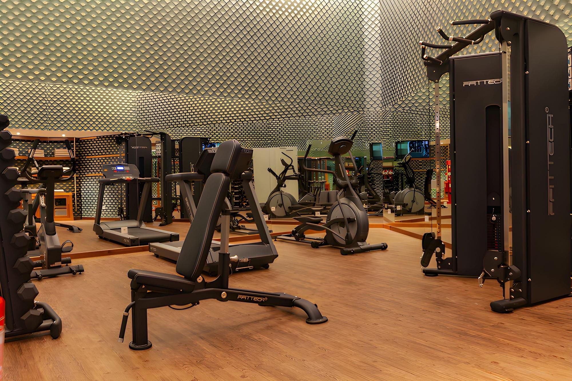 Een sportschool met diverse fitnessapparaten, waaronder loopbanden, elliptische trainers en krachtapparaten.