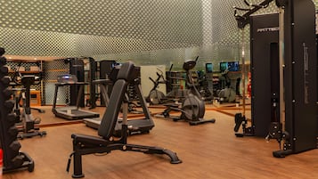 Een sportschool met diverse fitnessapparaten, waaronder loopbanden, elliptische trainers en krachtapparaten.