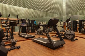 Et fitnessrum med løbebånd, crosstrainere og styrkemaskiner.