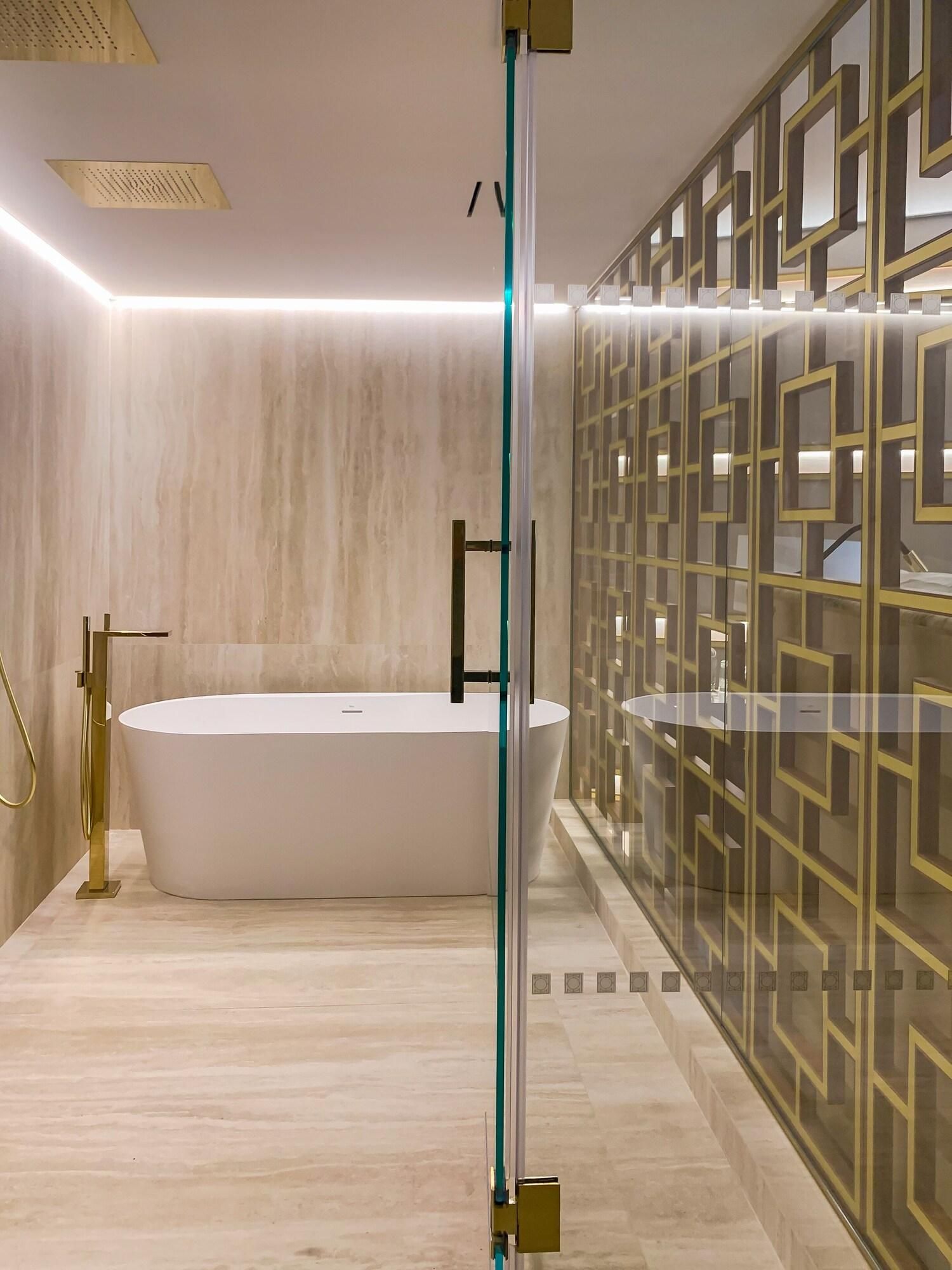 Un baño moderno con una bañera independiente, cabina de ducha con mampara de vidrio y un panel decorativo en la pared.