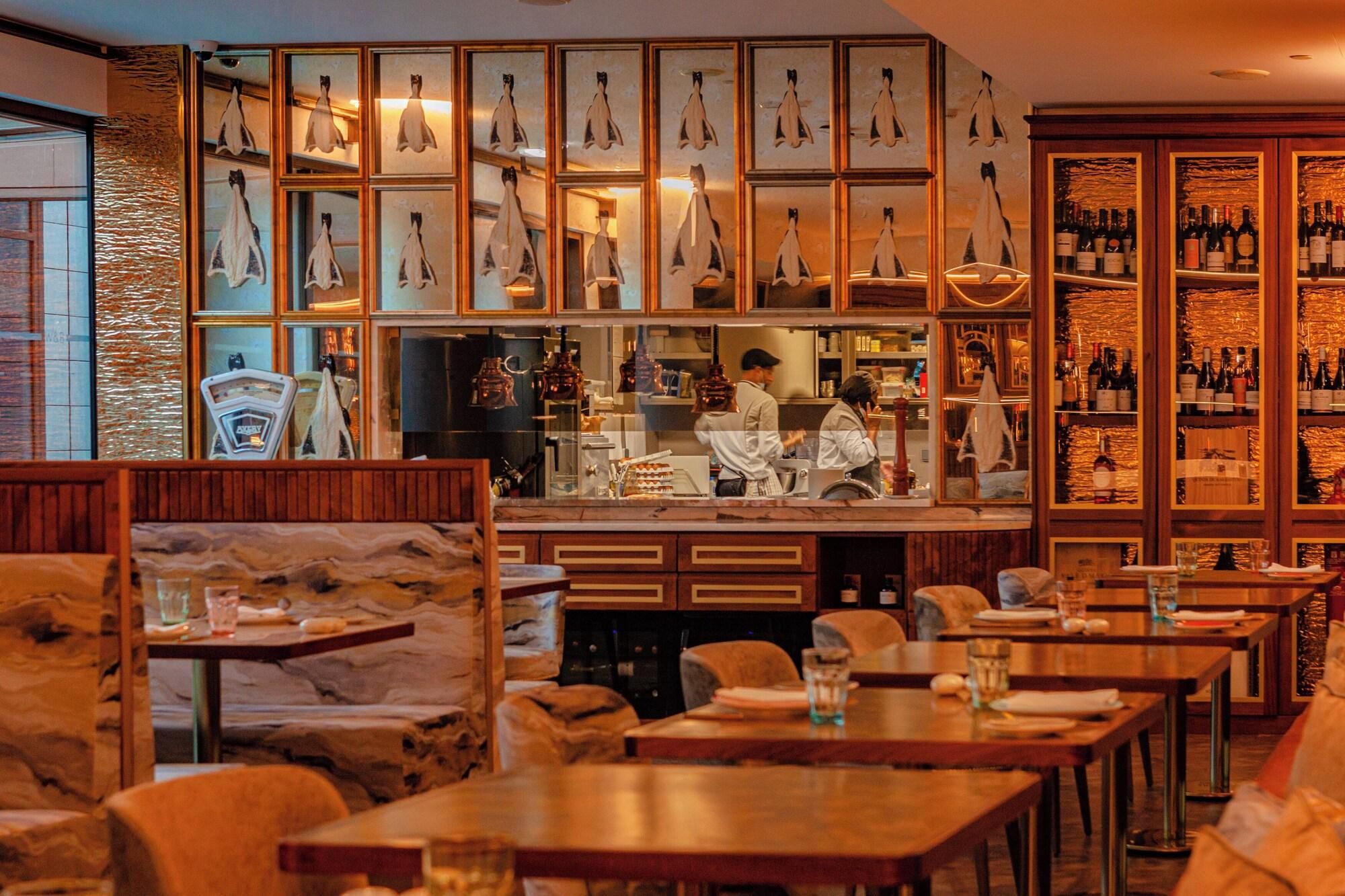Een restaurant met een bar, houten meubels en een etalage met pinguïnbeeldjes.
