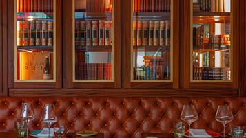 A leather booth with a view of a library with bookshelves and a bottle of wine.