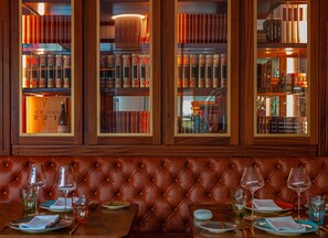Eine Lederausgabe mit Blick auf eine Bibliothek, die Bücherregale und eine Weinflasche zeigt.