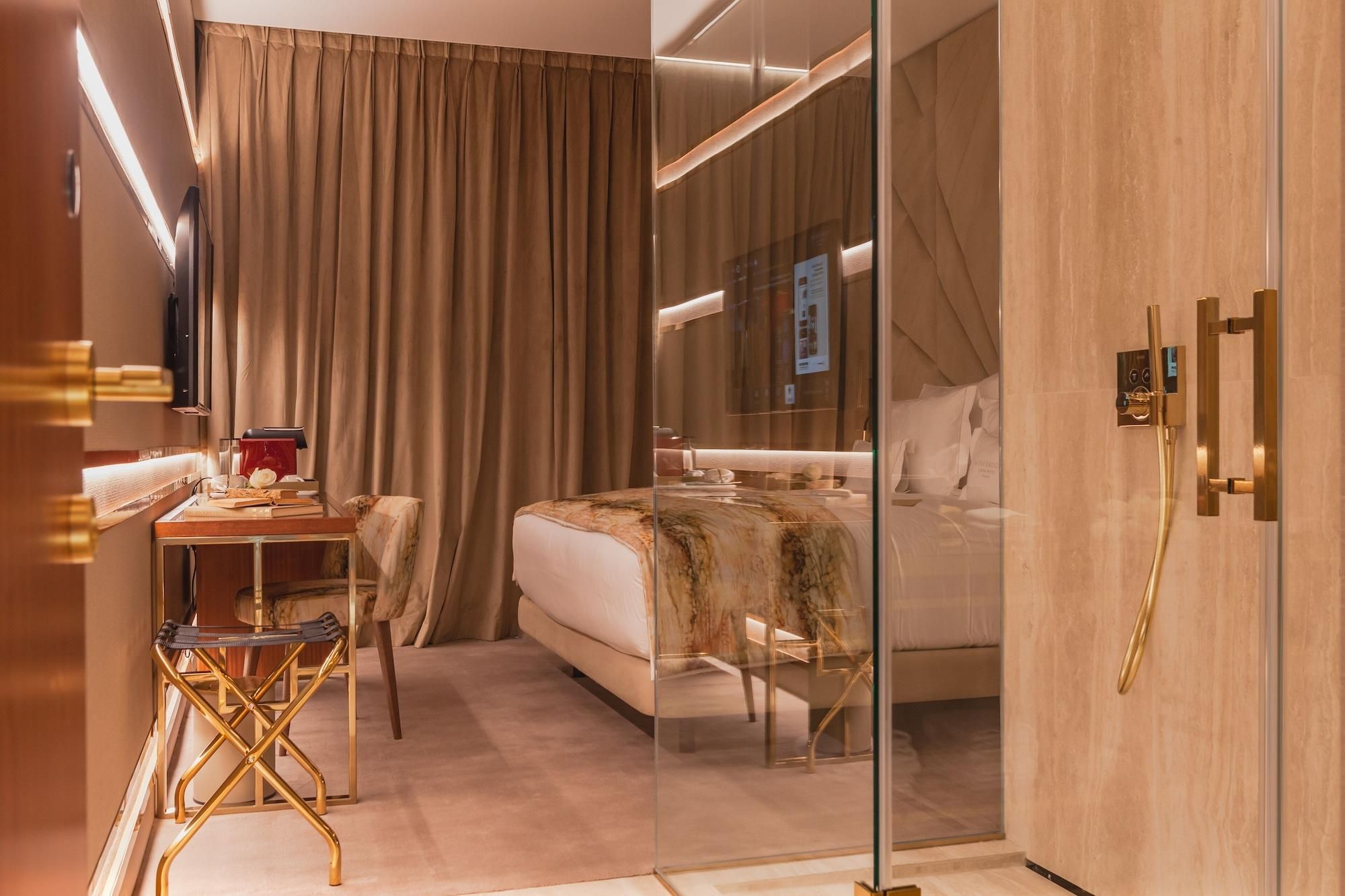 Una habitación de hotel moderna con una cama, un escritorio, una silla y un separador de vidrio.