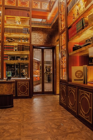 Een ruime lobby met houten vloeren, een receptiebalie en een grote glazen deur die leidt naar een bar.