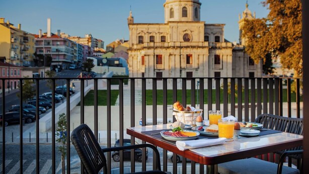 Ein Balkon mit Frühstückstisch, mit Blick auf eine Stadtlandschaft und historische Architektur.