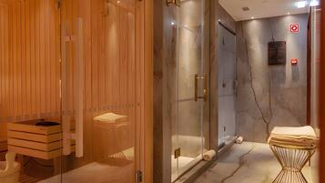 Un baño moderno con paneles de madera, cabina de ducha de vidrio y suelo de mármol.