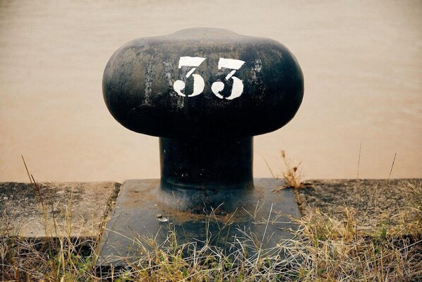 A black bollard with the number 33 painted on it. - Firstname Bordeaux (Bordeaux)