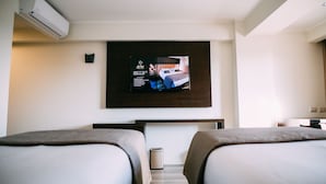 Une chambre d’hôtel avec deux lits, un téléviseur fixé au mur et un appareil de climatisation.