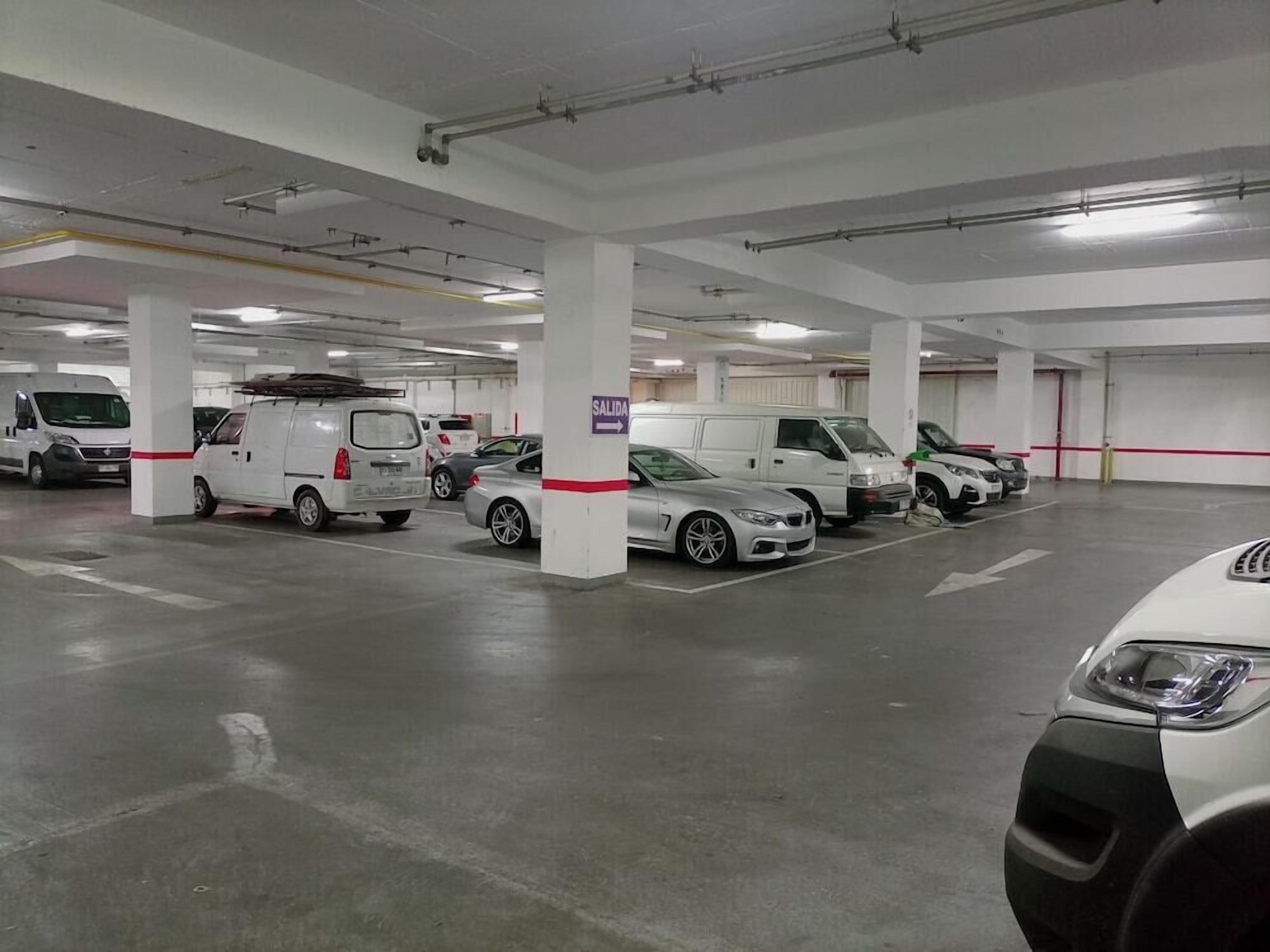 Un estacionamiento de varios niveles con pilares blancos y señalización clara.