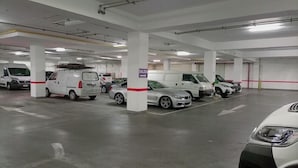 Un parking à plusieurs niveaux, doté de piliers blancs et d’une signalisation claire indiquant les directions.
