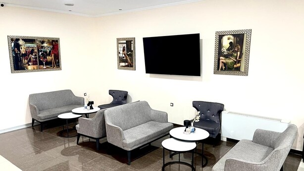 A modern waiting area with grey sofas, round tables, and artwork on the walls. - Kornilios Palace Thessaloniki (Chalkidona)