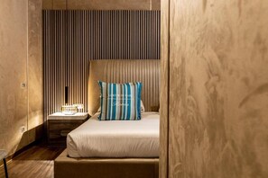A modern bedroom with a bed, a nightstand, and a striped pillow. - Le Reve De Naim (Florence)