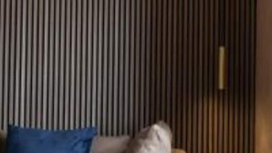 A sofa with a blue pillow and a grey pillow against a wall with vertical wooden slats. - Le Reve De Naim (Florence)