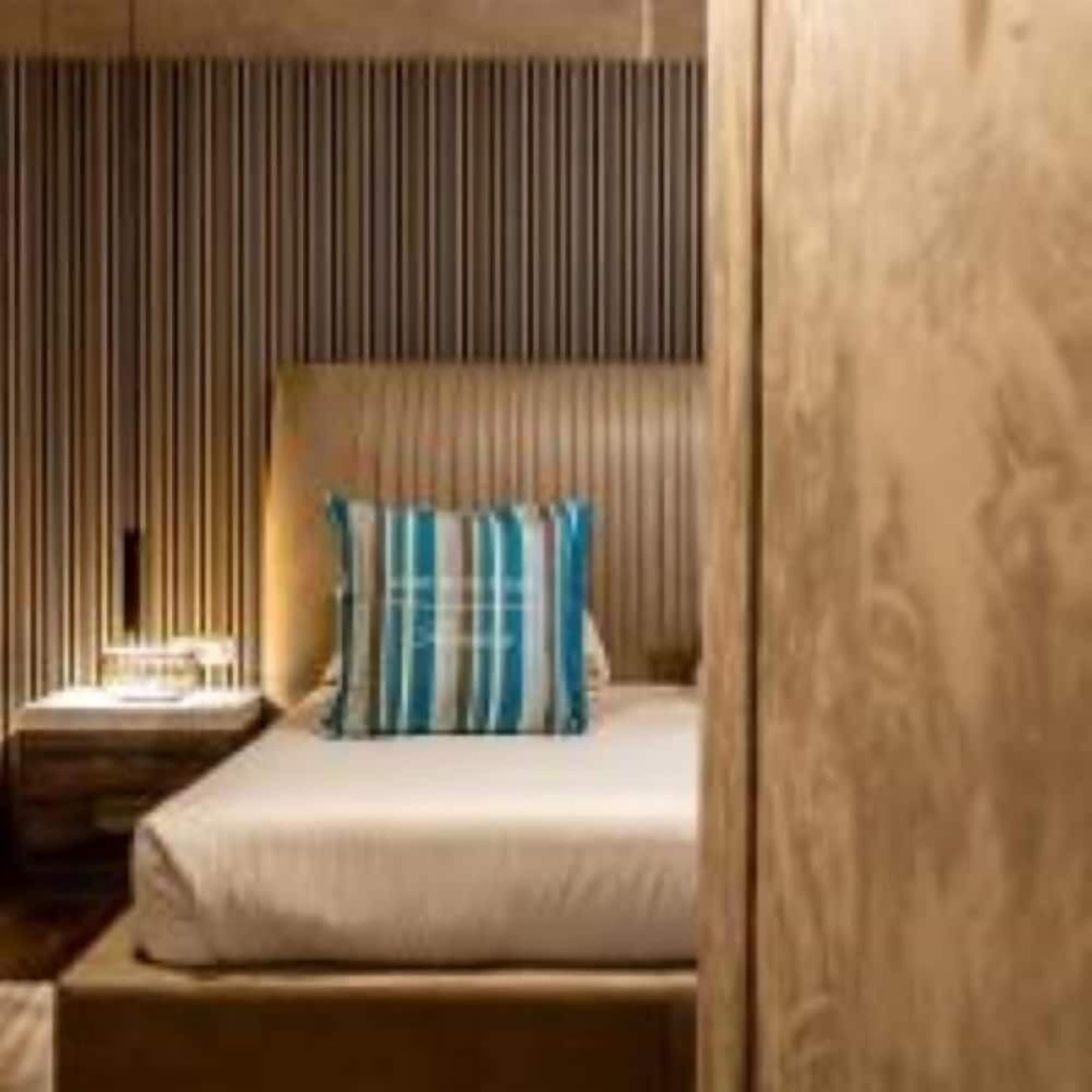 A bedroom with a bed, a nightstand, and a wall with vertical lines.