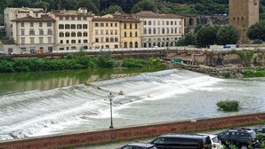 A river with a dam, buildings, and a tower. - Le Reve De Naim (Florence)