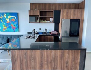 A modern kitchen with a central island, built-in appliances, and wooden cabinetry. - Angelina 28 Beachfront by Nah Hotels (Playa del Carmen)