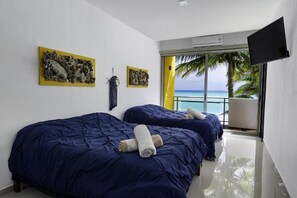 A hotel room with two beds, a TV, artwork on the walls, and a view of the ocean. - Angelina 28 Beachfront by Nah Hotels (Playa del Carmen)