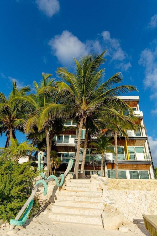 A multi-story building with a stone staircase leading up to a wooden deck. - Angelina 28 Beachfront by Nah Hotels (Playa del Carmen)