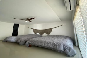 Ein Schlafzimmer mit zwei Betten, einem Deckenventilator und einem Fenster mit Jalousien.