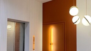 A modern hallway with a wooden door, a wall-mounted light fixture, and a ceiling light. - Woco Hotel Kinrara (Puchong)