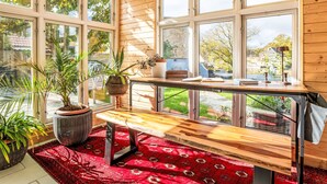 A sunlit room with large windows, a wooden bench, and potted plants. - Das königliche Quartier by Interhome (Mirow)