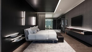 A modern bedroom with a large bed, bedside tables, a TV, and a glass-enclosed bathroom. - Hotel Alexander (Mexico City)