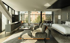A modern living room with a sofa, a TV, a dining area, and a bedroom with a bed. - Hotel Alexander (Mexico City)
