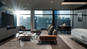 A modern living room with a sofa, coffee table, and dining area. - Hotel Alexander (Mexico City)