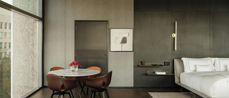 A modern bedroom with a bed, a bedside table, a nightstand, and a wall-mounted light fixture.