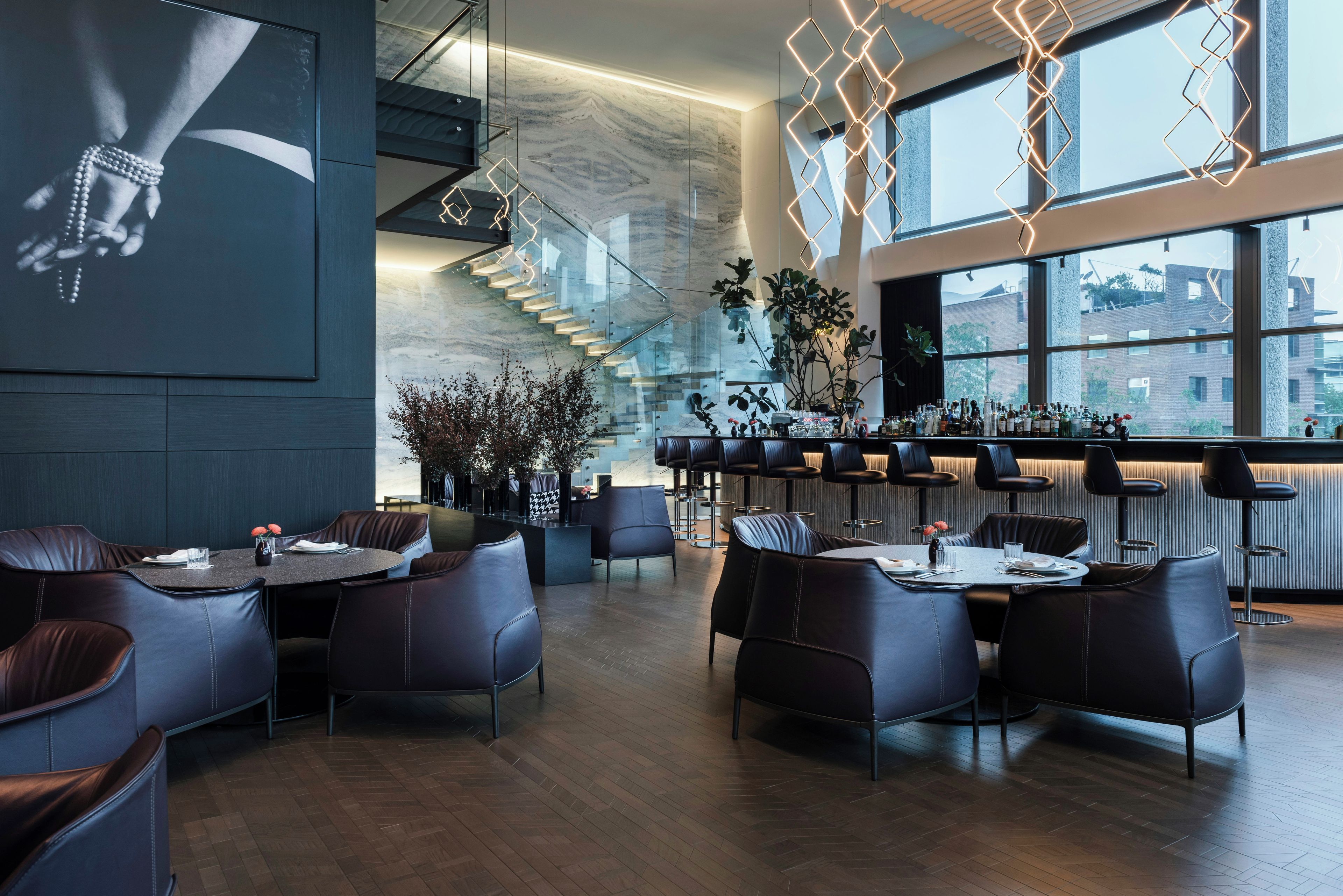 Un ristorante moderno con zona bar, sedute in pelle e una scalinata.