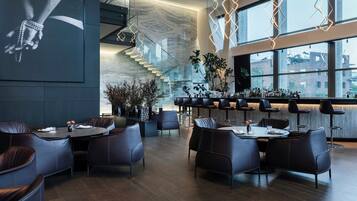 Restaurante moderno com área de bar, assentos de couro e uma escadaria.
