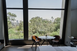 A room with a large window, two chairs, a small table, and a bed. - Hotel Alexander (Mexico City)