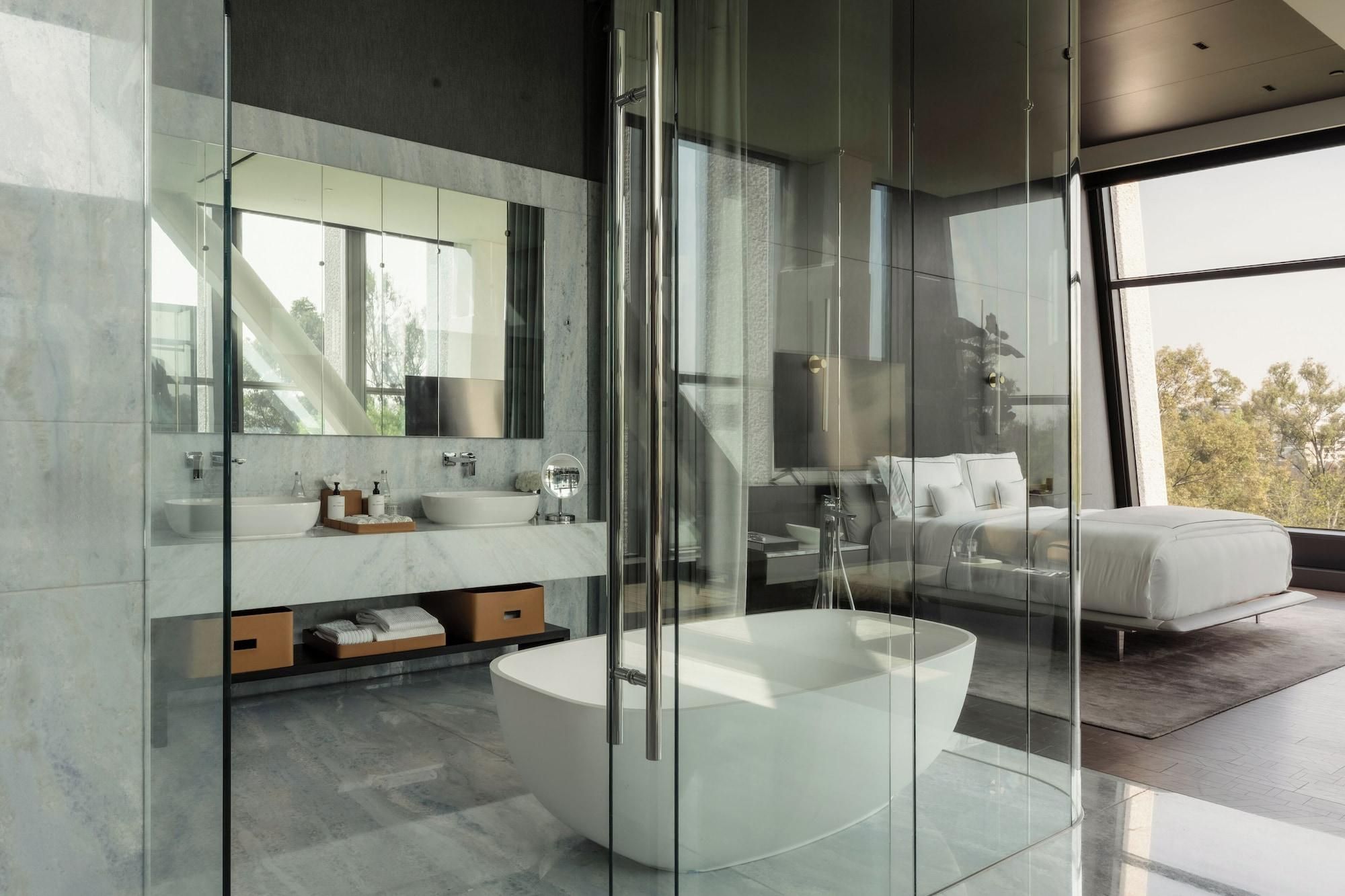 A modern bathroom with a glass-enclosed shower, a large bathtub, and a mirrored vanity.