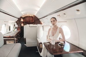 A private jet interior with a dining area, a bar, and a seating area. - Hotel Alexander (Mexico City)