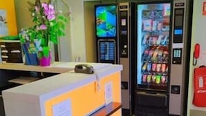 A reception area with a counter, a vending machine, and a potted plant. - Premiere Classe Troyes Sud - Parc St Thibault (Bucheres)
