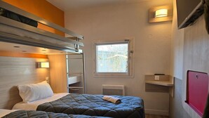 A compact hotel room with two beds, a window, a radiator, and a small shelf. - Premiere Classe Troyes Sud - Parc St Thibault (Bucheres)