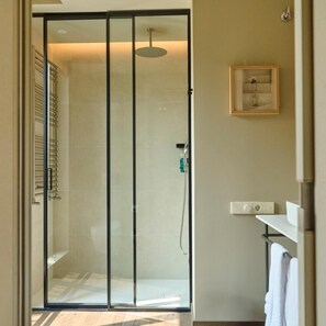 Un bagno moderno con cabina doccia in vetro, un quadro appeso al muro e un porta asciugamani.