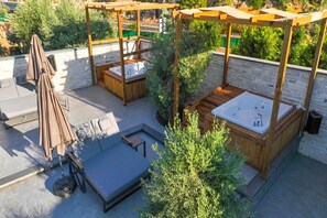 Una terrazza sul tetto con due vasche idromassaggio, un'area salotto e un ombrellone.