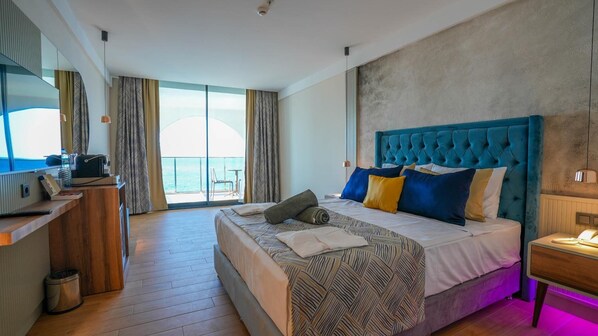 Habitación de hotel con una cama grande, un escritorio, una silla y vista al mar.