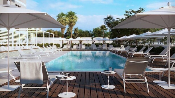 A poolside area with lounge chairs and umbrellas, surrounded by greenery and a clear sky. - B21 Hotel (Bari)
